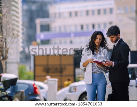 Happy couple of executives talking and conversing on the street with an office building in the background