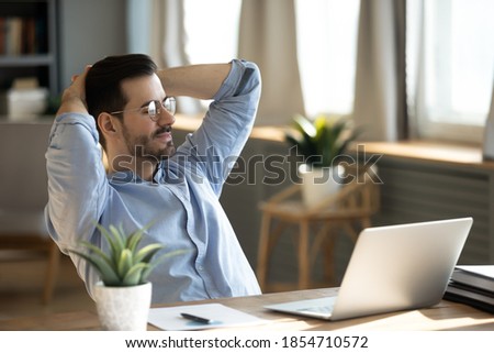 Handsome young businessman resting at workplace lean on comfort chair closed eyes enjoy fresh conditioned air. Satisfied employee finish work feels serene relaxing in modern office, no stress concept Royalty-Free Stock Photo #1854710572