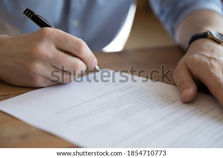 Bank client sitting at table holds pen put signature confirm document, signing loan application, close up hands and agreement view. Make legal profitable transaction, successful business deal concept Royalty-Free Stock Photo #1854710773