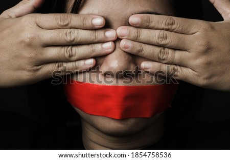 Asian woman blindfold wrapping mouth with red adhesive tape on black background. Freedom speech censorship and stop talk, International Human Right day Royalty-Free Stock Photo #1854758536