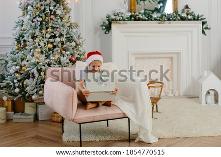 a seven-year-old boy sits in the New Year's interior and opens a gift. christmas and new year concept. High quality photo