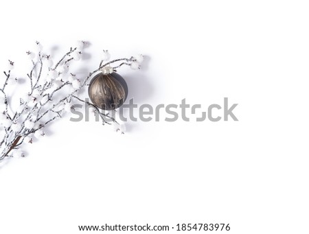 Modern winter mockup of a snow covered branch and a glass ball with creative black and gold coloring. Minimalistic template for christmas, new year, invitation, banner. Flat lay, top view, copy space.