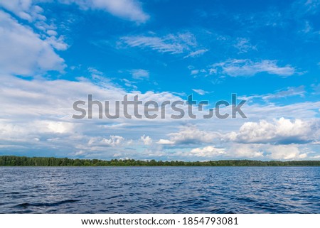 Wonderful landscape with blue tranquil empty river surface with rippling surface under bright blue sky with fluffy white clouds on nice sunny summer day.