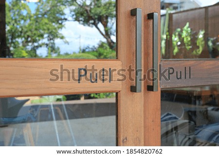 Closeup glass door of cafe with text pull on wood