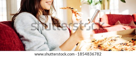 Portrait of handsome woman eating pizza at home and taking photo of her food to share memory