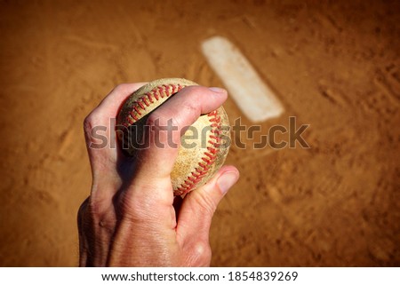 Pitcher holding baseball with mound in background                              