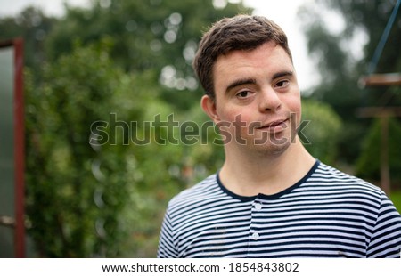 Portrait of down syndrome adult man standing outdoors in garden. Royalty-Free Stock Photo #1854843802