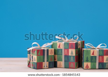 Gifts in boxes, wrapped in paper with Christmas and New Year pictures. Holiday souvenirs on  blue background.