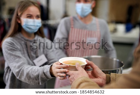 Volunteers serving hot soup for homeless in community charity donation center, coronavirus concept. Royalty-Free Stock Photo #1854854632