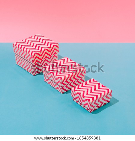 Bright striped gift boxes on a blue and pink pastel background in the line. Concept of a holiday, Christmas, new year or birthday.