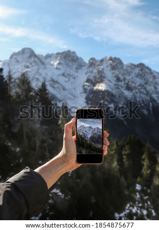 Back view of a woman is taking photo with cell telephone camera of an amazing jungle landscape.