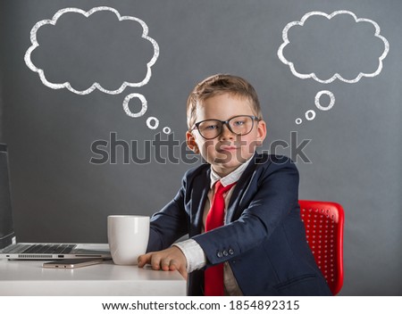 Kid businessman at work in office. Child in suit in gray wall background. Thinking kid with picture of clouds.