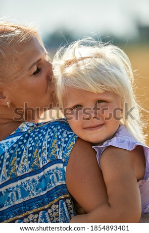 happy mother holding baby smiling on a wheat field in sunlight