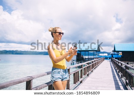 Millennial female tourist in sunglasses searching information about public coastline for visiting during summer vacations in Thailand, attractive woman connecting to 4g for checking chat updation