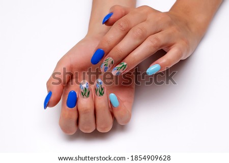 Dark blue, light blue manicure with painted summer flowers on oval long nails close-up on a white background.	