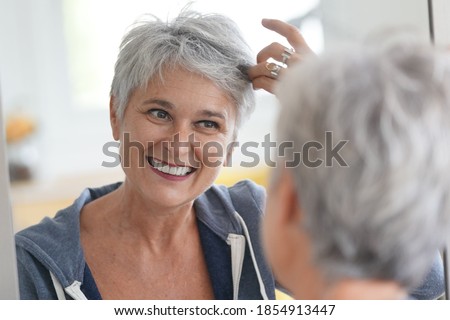 senior woman looking at that white hair in a mirror Royalty-Free Stock Photo #1854913447