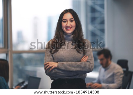 Beautiful smiling young Turkish woman in a modern office with her colleagues.