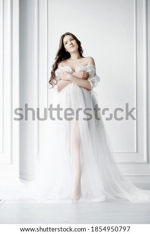 beautiful young pregnant woman in long white negligee