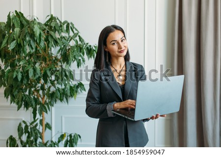 young beautiful girl with Asian appearance, she conducts a web conference at home, she has a laptop and a phone in her hands