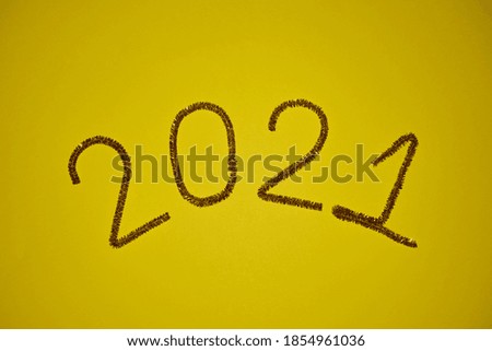 New year 2021 inscription made of glittering tinsel with a yellow background.                         