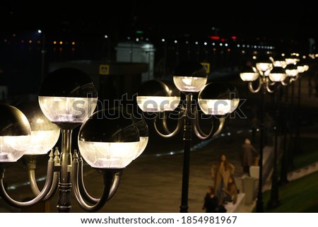 Lanterns on the square.Glow at night.A row of lamps light in the dark.Beautiful art photography.Background image