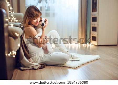 Girl sitting on floor in christmas living room hugging her dog