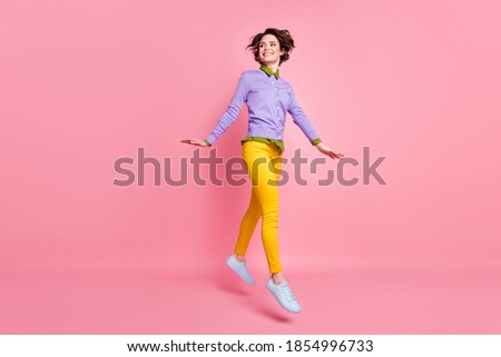 Full size photo of cheerful lady jump up good mood wear jumper yellow pants sneakers isolated pink color background
