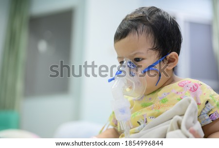 Asian baby was sick as Respiratory Syncytial Virus (RSV) in kid hospital. Thai little girl having inhaler containing medicine for stop coughing and disease flu. Royalty-Free Stock Photo #1854996844