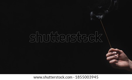 hand with incense stick on dark background