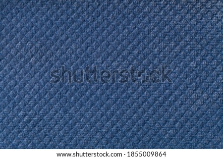 Texture of navy blue fluffy fabric background with rhomboid pattern, macro. Abstract backdrop from decorative denim woven textile material.