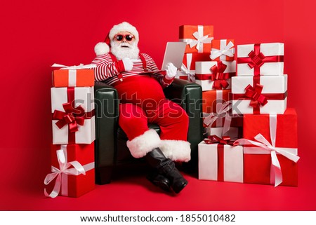Photo of old man sit armchair indicate finger computer wear x-mas costume isolated decorated red color background