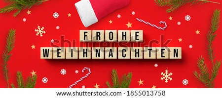 cubes with German message for MERRY CHRISTMAS and christmas decoration on red background