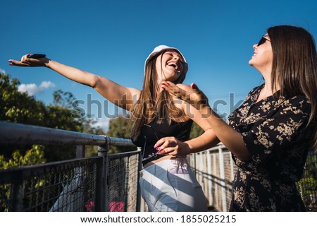 Lovely girls laughing with arms up - Beautiful girls having fun outdoors on a sunny day.