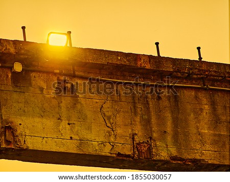 Concrete and metal element with rust and with light sources on a clear sky background.