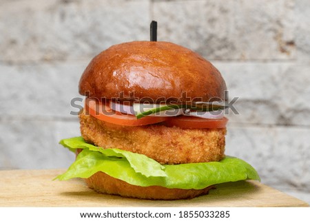 Fish burger with salad on a wooden board