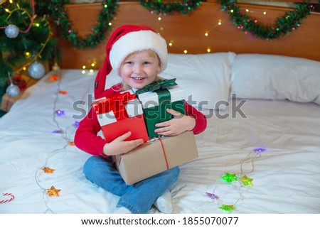 Happy little girl in Santa Claus hat received a Christmas present at home. Christmas kid,child. Selective focus.