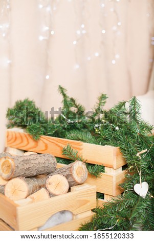 
wooden boxes with firewood and christmas tree branches close-up on a beige background
naturalness decor christmas interior details scandi style