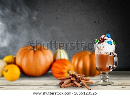 Pumpkin hot drink. Autumn drink with spicy pumpkin flavor with pumpkins on a background.