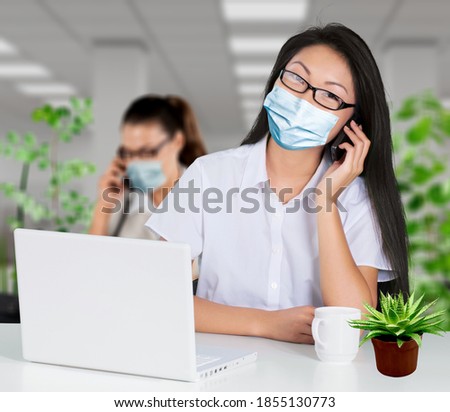 Return to work after covid-19 quarantine. Busy millennial woman in protective mask talking on phone