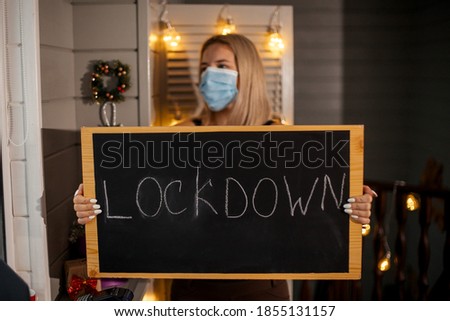  Woman waiter in protective mask taking in hands nameplate Lockdown. She depressed and worried about losing her job