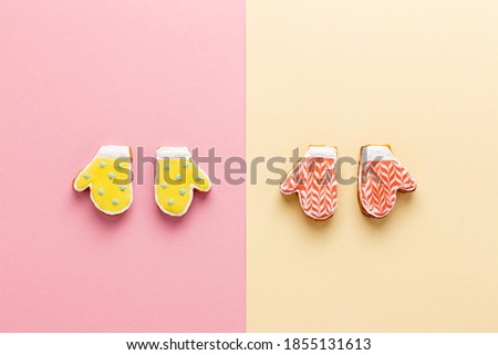 Christmas mitten-shaped gingerbread with icing on trendy pink and yellow background