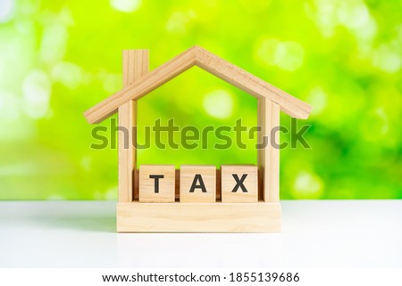 House model with tax wooden block and green nature background, Housing tax concept