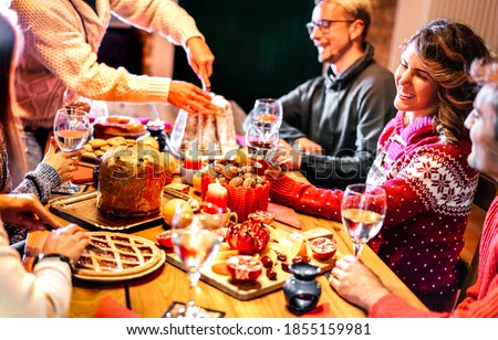 Happy young friends tasting Christmas sweet food having fun at home supper party - Winter friendship concept with millenial people enjoying new year's eve dinner eating together - Warm filter