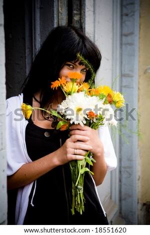 Girl with bouquet standing near door hiding face