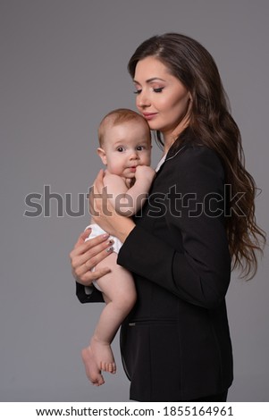 Happy smiling mother with baby on gray background.Happy family  and motherhood concept

