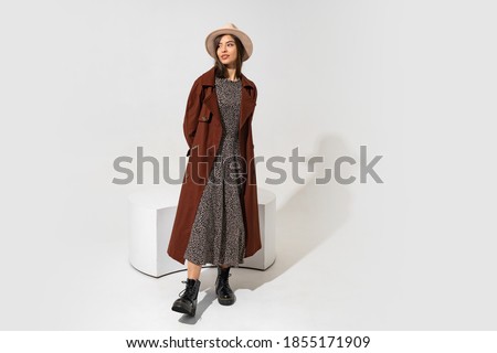 Winer fashion look. Stylish brunette model in brown coat  and ankle boot in black leather  posing in studio on white background. Full lenght. Copyspace fo text.
