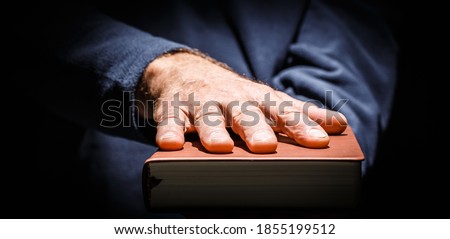 Male hand laid on top of a hardcover book oath taking concert. Horizontal photo banner. Royalty-Free Stock Photo #1855199512