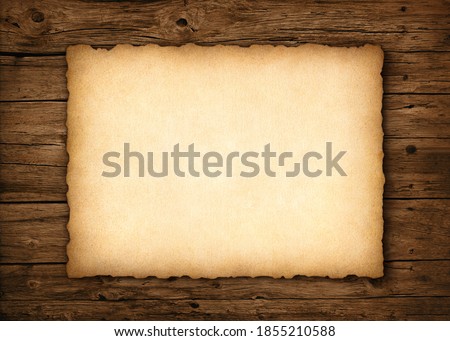 Old parchment with worn edges on a rustic wood background Royalty-Free Stock Photo #1855210588