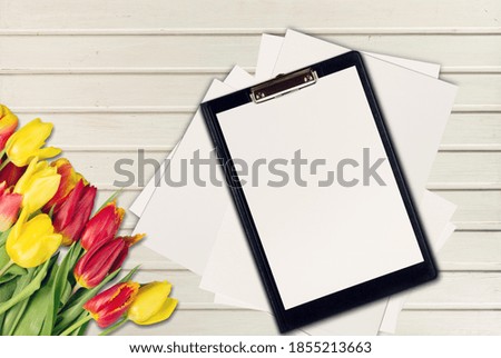 Blank paper sheet clipboard tablet pad with fresh  flowers on the desk