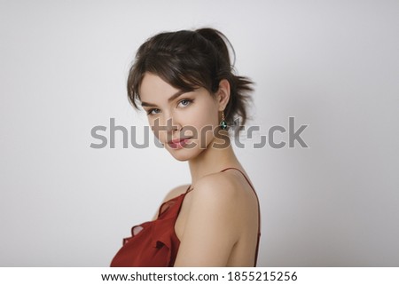 Beauty portrait of female face with natural perfect skin. Studio portrait of a beautiful young woman with brown hair in red dress.